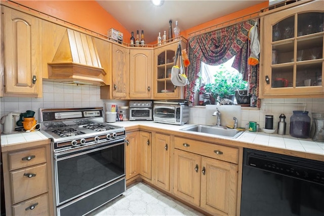 kitchen featuring tile countertops, premium range hood, a sink, black dishwasher, and gas range oven