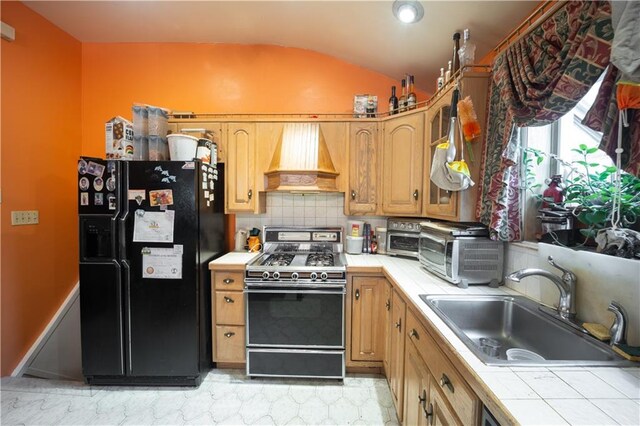 kitchen with sink, premium range hood, tile counters, gas range oven, and black fridge with ice dispenser