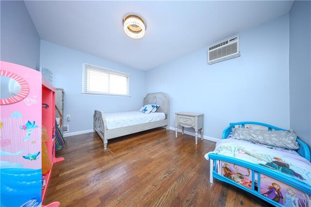 bedroom featuring dark hardwood / wood-style floors and a wall unit AC