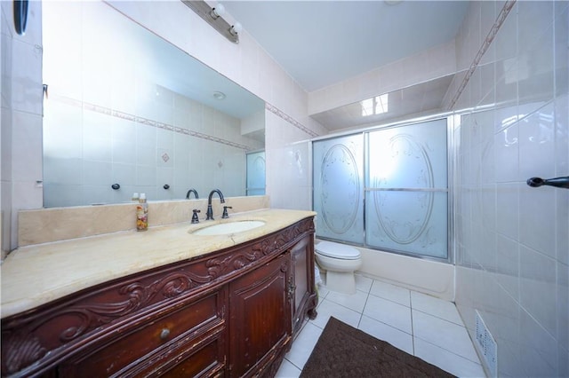 full bathroom with tile patterned floors, vanity, tile walls, enclosed tub / shower combo, and toilet