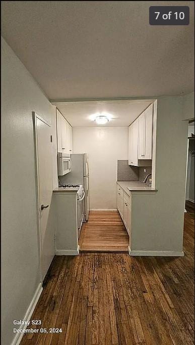 kitchen with backsplash, white cabinetry, and dark wood-type flooring