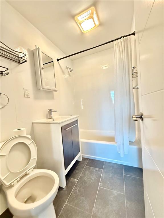 full bathroom featuring tile patterned floors, shower / bath combo, toilet, and vanity