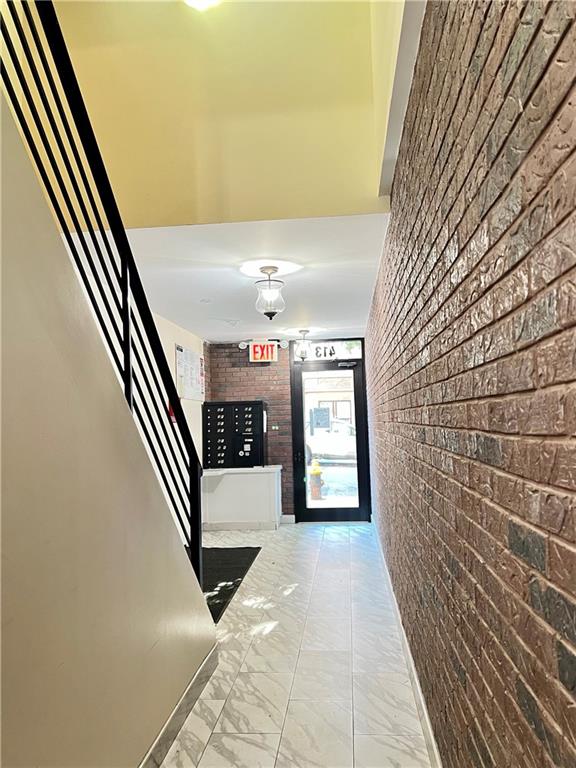 hall featuring mail boxes and brick wall