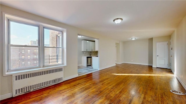 unfurnished living room featuring radiator heating unit and hardwood / wood-style floors