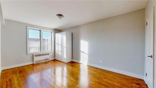 empty room featuring radiator heating unit and light hardwood / wood-style floors