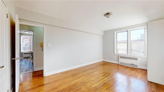 empty room with radiator heating unit and light hardwood / wood-style flooring