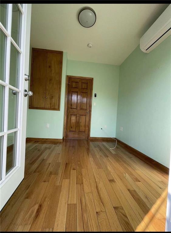 unfurnished room featuring light hardwood / wood-style flooring and an AC wall unit