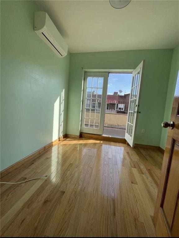 spare room with light wood-type flooring and an AC wall unit