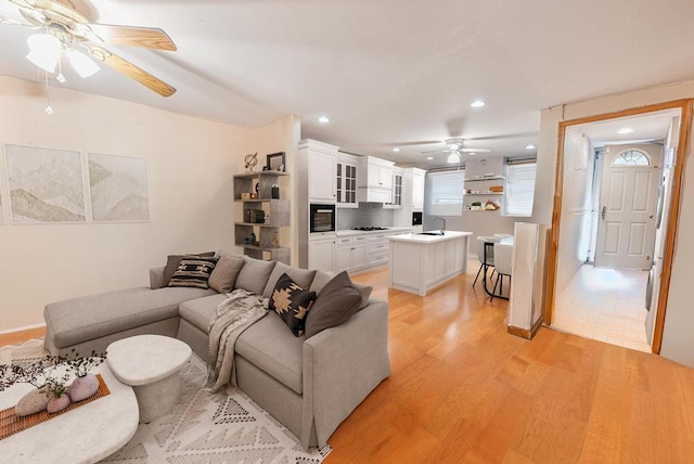 living room with ceiling fan, sink, and light hardwood / wood-style flooring