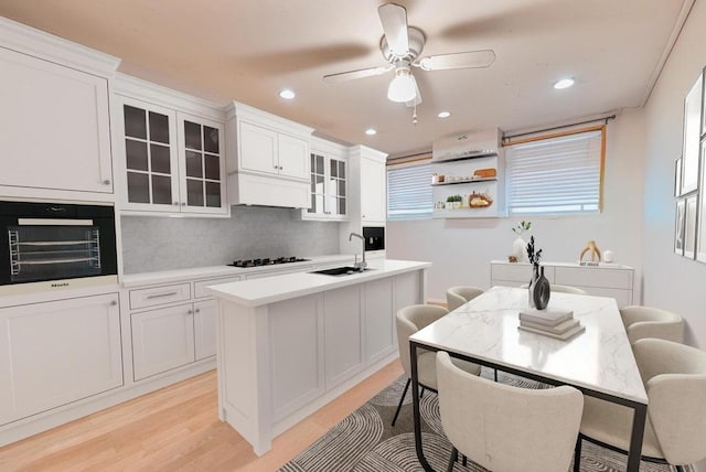 kitchen featuring sink, a center island with sink, white cabinets, and black appliances