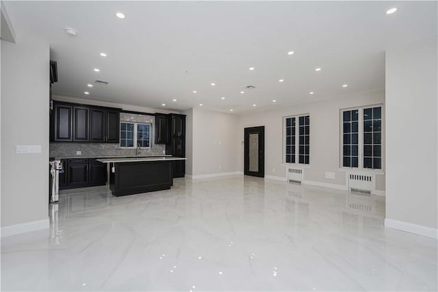 kitchen with a breakfast bar area, a center island, radiator heating unit, and backsplash