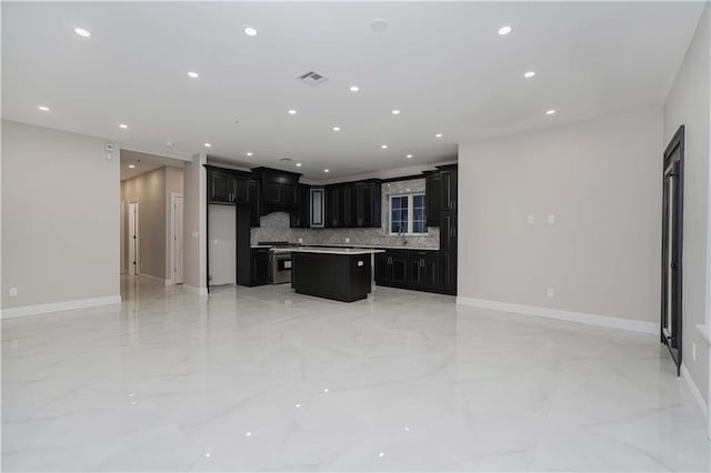 kitchen with visible vents, a kitchen island, open floor plan, light countertops, and dark cabinetry