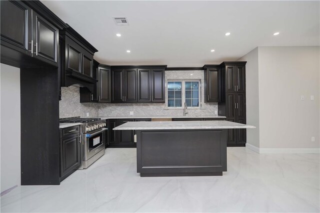 kitchen with high end stainless steel range oven, a center island, sink, and decorative backsplash