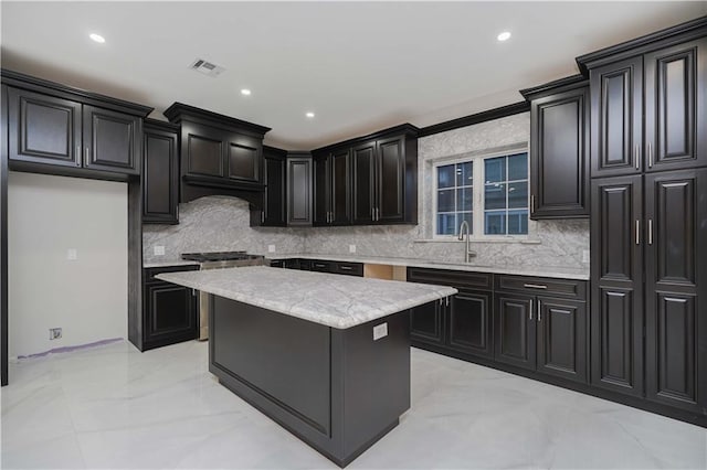 kitchen featuring a sink, visible vents, a center island, marble finish floor, and decorative backsplash