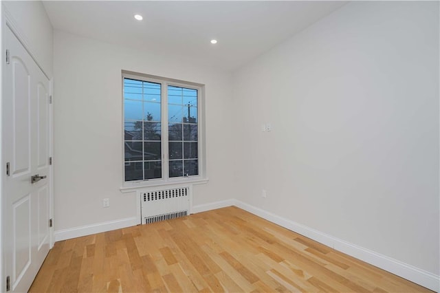 unfurnished room featuring radiator and light wood-type flooring