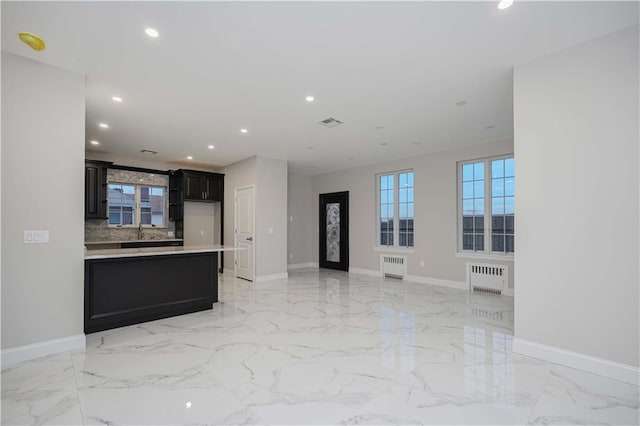 unfurnished living room featuring marble finish floor, radiator heating unit, and baseboards