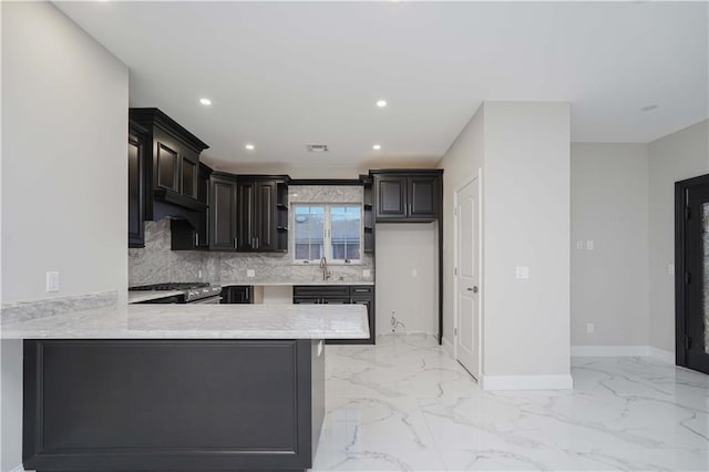 kitchen featuring a peninsula, a sink, marble finish floor, light countertops, and high end range