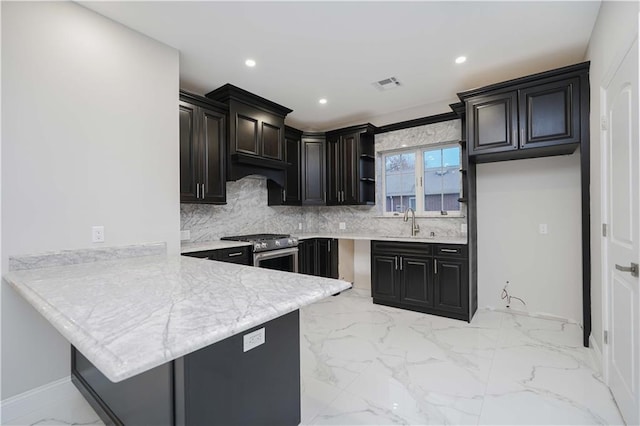 kitchen with a peninsula, a sink, marble finish floor, light countertops, and high end range