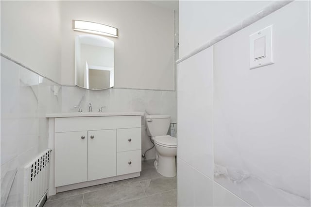 bathroom with tile walls, radiator heating unit, vanity, tile patterned floors, and toilet