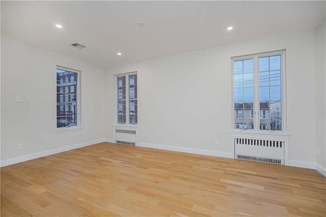 spare room featuring recessed lighting, radiator, light wood-style flooring, and baseboards