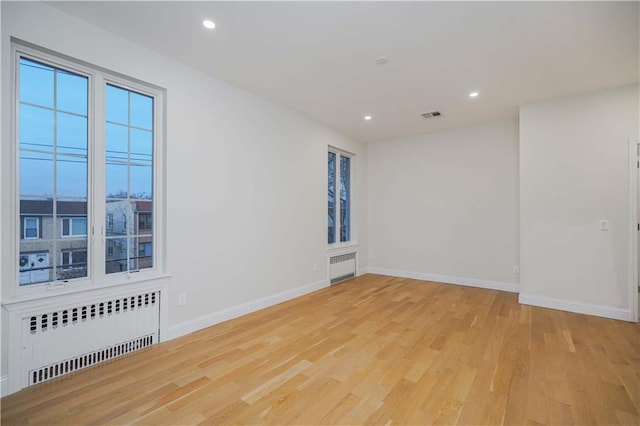 spare room with recessed lighting, radiator, visible vents, and light wood finished floors