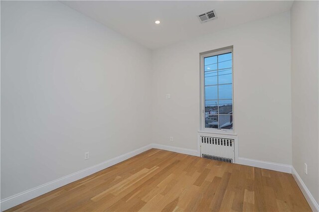 empty room with radiator and hardwood / wood-style flooring