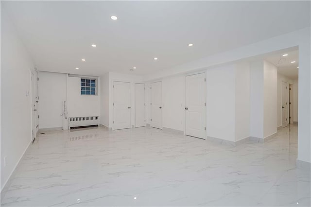 empty room with marble finish floor, radiator heating unit, baseboards, and recessed lighting