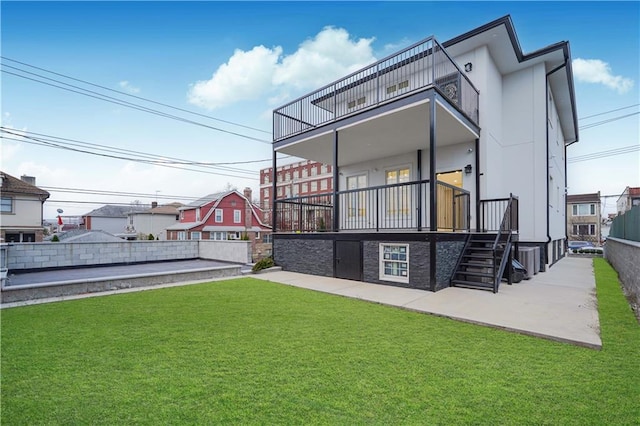 rear view of house with a balcony, stairway, a lawn, and a patio