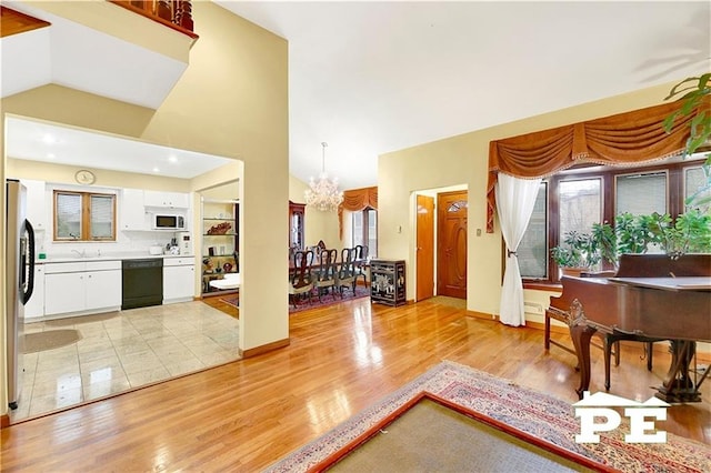 entryway featuring vaulted ceiling, light wood-style flooring, and an inviting chandelier