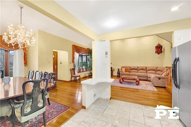 living area featuring a chandelier, baseboards, a healthy amount of sunlight, and light wood finished floors