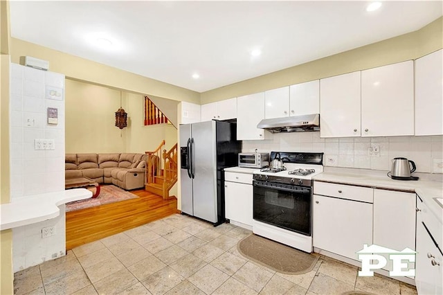 kitchen with white gas range, light countertops, backsplash, under cabinet range hood, and stainless steel fridge with ice dispenser