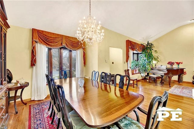 dining area featuring lofted ceiling, baseboards, wood finished floors, and an inviting chandelier