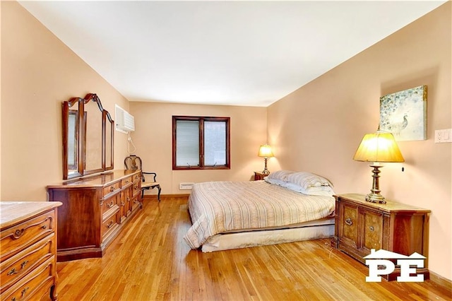 bedroom featuring a wall mounted air conditioner and light wood-style flooring