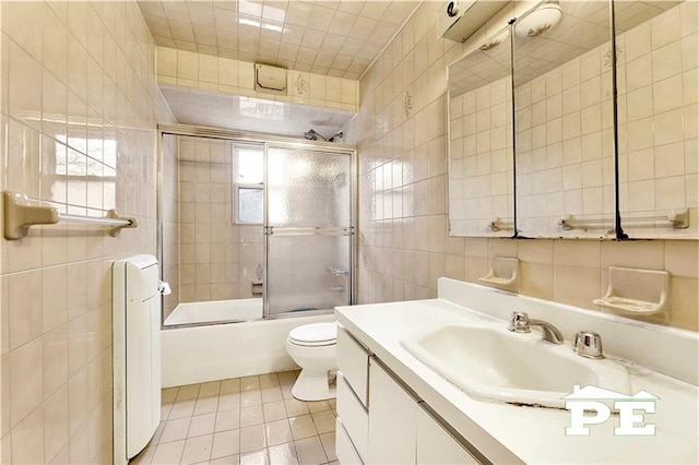 full bath featuring toilet, vanity, tile walls, and tile patterned floors