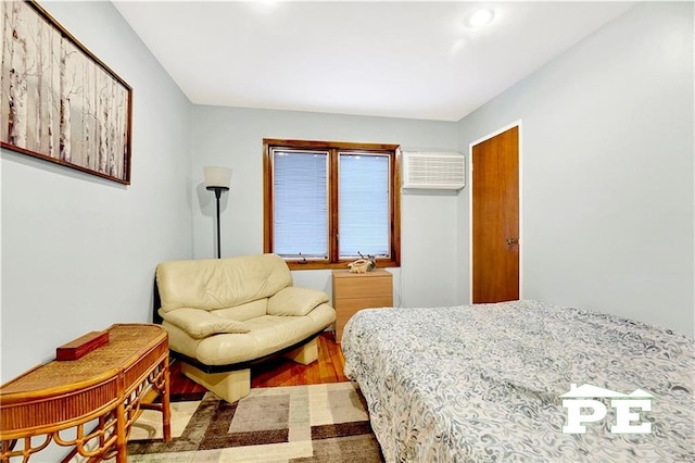 bedroom with a wall mounted AC and wood finished floors