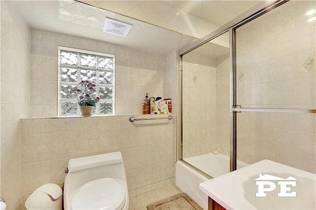 full bath featuring visible vents, tile walls, toilet, and combined bath / shower with glass door