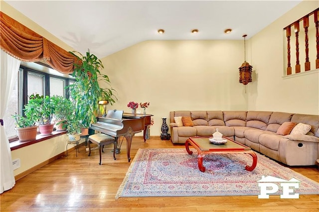 living area featuring lofted ceiling, wood finished floors, and baseboards