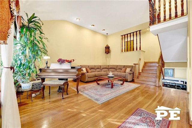 living area featuring stairs, lofted ceiling, and wood finished floors