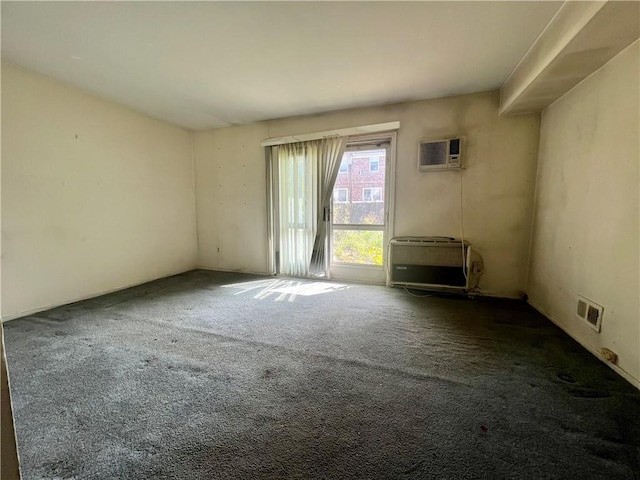 carpeted spare room featuring visible vents, heating unit, and an AC wall unit