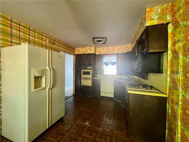 kitchen with white appliances, dark brown cabinetry, sink, and dark parquet floors