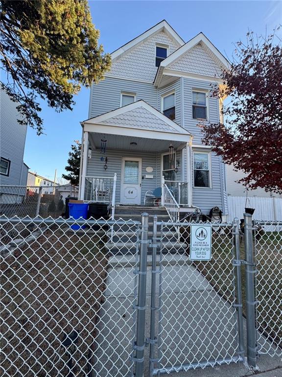 multi unit property featuring covered porch, a fenced front yard, and a gate