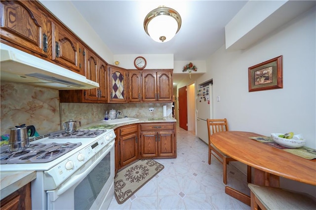 kitchen with decorative backsplash, white appliances, and sink