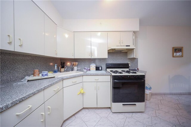 kitchen with tasteful backsplash, white cabinets, and white range with gas stovetop