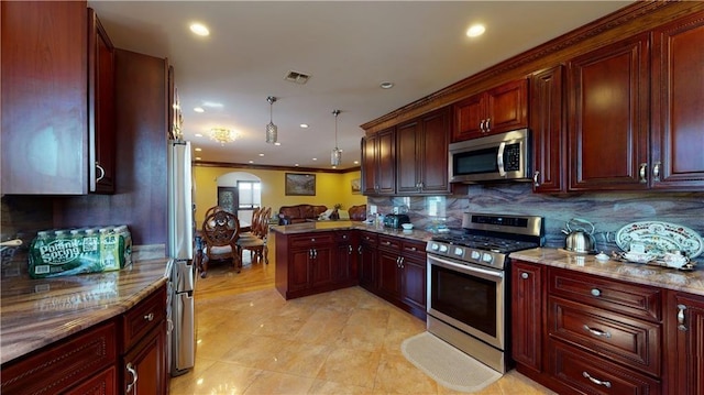 kitchen featuring light stone countertops, decorative light fixtures, decorative backsplash, appliances with stainless steel finishes, and ornamental molding