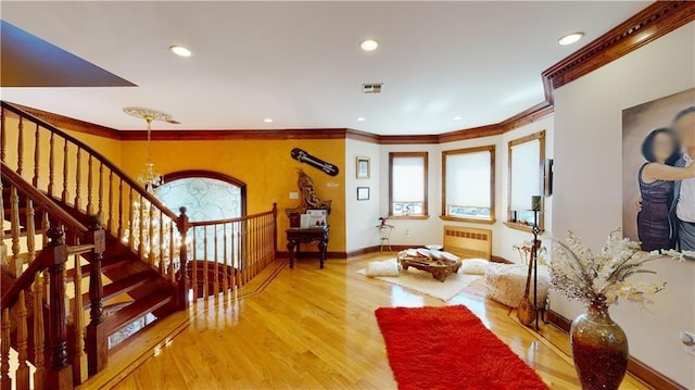 interior space with light wood-type flooring, ornamental molding, radiator, and an inviting chandelier