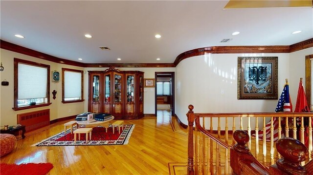 interior space featuring wood-type flooring, radiator, and ornamental molding