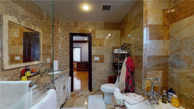 bathroom with vanity, toilet, and tile walls