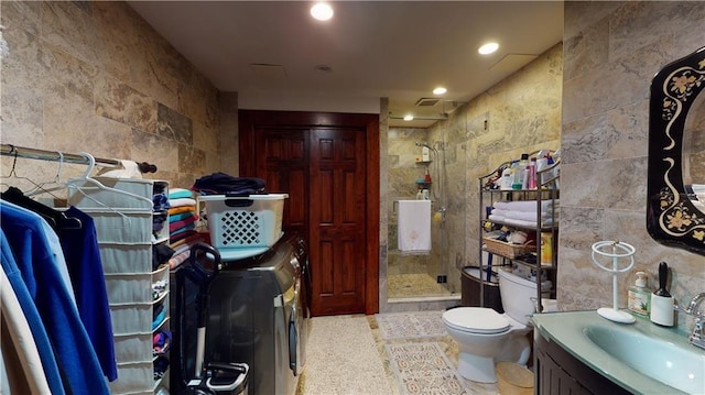 bathroom featuring vanity, washing machine and dryer, toilet, and walk in shower