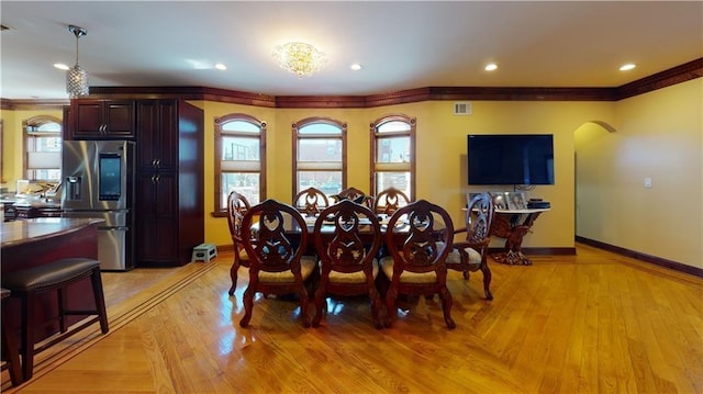 dining area featuring light wood-type flooring and ornamental molding