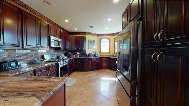 kitchen featuring stainless steel appliances, light stone counters, backsplash, kitchen peninsula, and crown molding